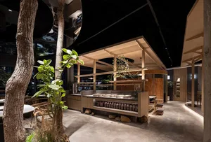 Warm and inviting restaurant interior with wooden tables and countertops, potted plants, and well-lit atmosphere