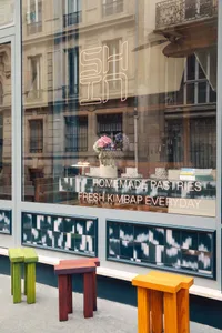 A bakery shop interior with cakes and pastries on display, a vase, and a welcoming atmosphere