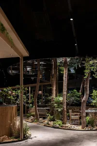 A restaurant interior with potted plants, comfortable seating, and dining tables, creating a relaxed atmosphere