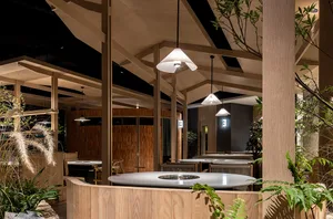 Warm and inviting restaurant space with wooden floors and walls, featuring tables, chairs, and potted plants