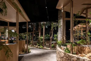A restaurant interior with potted plants, chairs, and dining tables, creating a warm and inviting atmosphere