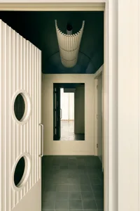 A calm and inviting hallway with white walls and flooring, featuring two doors and a clean appearance