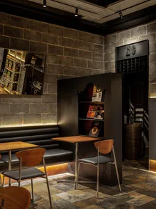 Modern restaurant interior with a dining area, bar, and bookshelf, featuring a warm and inviting atmosphere