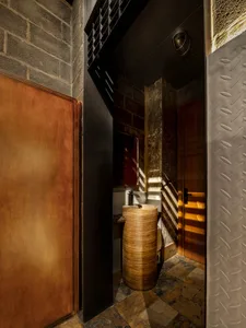 Bathroom with two sinks, a toilet, and brick walls in a dimly lit space