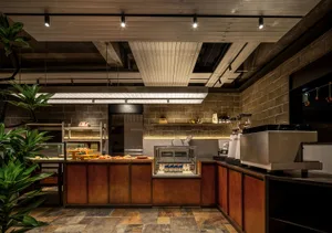 Industrial kitchen with a counter featuring food items, sinks, and a potted plant, set against a rendered background