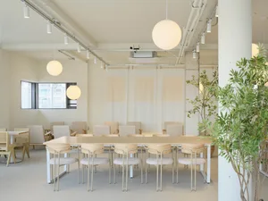 A long wooden table surrounded by multiple chairs in a clean and organized dining area, ready for guests
