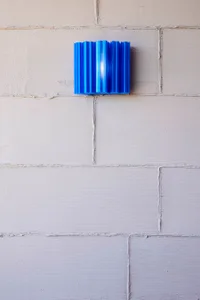 A blue light fixture on a white wall in an urban setting, creating a sense of depth and contrast with a calm and inviting atmosphere