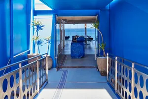 A bright and inviting open space with a blue accent wall, potted plants, and scattered chairs, suggesting a dining or gathering area