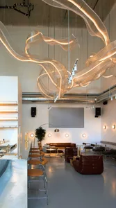 A spacious cafe with multiple tables and chairs, potted plants, and a clean modern atmosphere