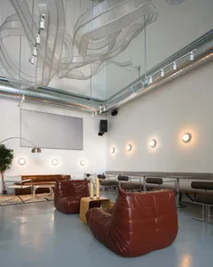 A large room with high ceilings, featuring couches, chairs, and dining tables, creating an inviting atmosphere for socializing and relaxation