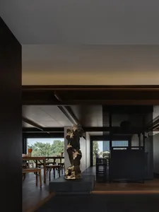 Dining area with a table and chairs, surrounded by a large window, a vase, and comfortable seating