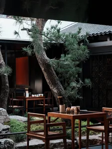 A warm and inviting restaurant interior with wooden tables and chairs, featuring dining tables with cups and bowls, creating a cozy atmosphere for patrons to enjoy their meals