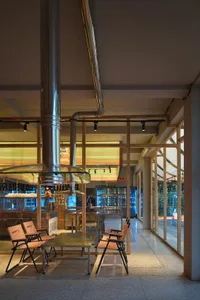 Modern restaurant interior with a large dining area, multiple chairs, and benches, featuring a warm and inviting atmosphere with soft lighting
