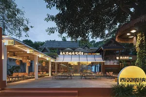 A nighttime outdoor restaurant scene with multiple dining tables and chairs, surrounded by lights and a relaxed atmosphere