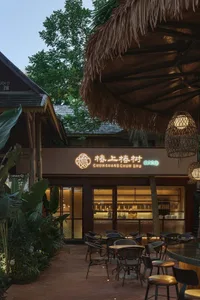 A warm and inviting Asian restaurant with a thatched roof, featuring tables, chairs, and cups, creating a comfortable dining atmosphere
