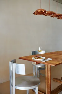A calm and inviting dining area with a wooden table, four chairs, wine glasses, and a bottle, surrounded by warm wooden elements