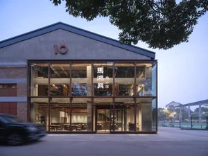 A modern Asian restaurant with a dining area featuring wood and concrete textures, clean lines, and minimalistic decorations, creating a cozy ambiance with warm lighting