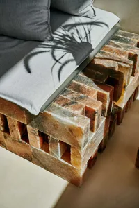 Cozy bedroom with a brick-patterned bench, two cushions, a potted plant, and a warm atmosphere