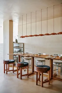 A warm and inviting dining area with a large wooden table, multiple chairs, and a rustic atmosphere, set up for a dinner party with wine glasses and cups scattered around the table