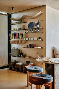 Cozy living space with a dining table surrounded by chairs, featuring wine glasses, vases, and a bookshelf, creating a warm and inviting atmosphere