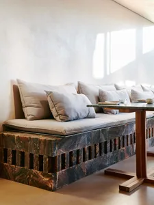 A cozy living area with a couch, dining table, and chairs, surrounded by comfortable pillows and inviting ambiance