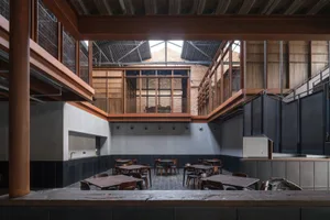 A casual restaurant dining area with multiple wooden tables and chairs, well-distributed lighting, and a warm atmosphere