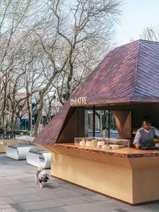 A casual outdoor cafe with a small house-like design, featuring wooden furniture and a welcoming atmosphere