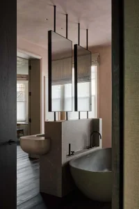 Bathroom with a marble sink, modern bathtub, mirror, and natural light from a window