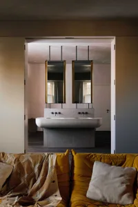 Bathroom with a marble countertop, two faucets, two mirrors, and a wooden floor, well-lit