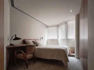 Bright and inviting bedroom with two beds, a desk area, and a chair, lit by natural light from a large window