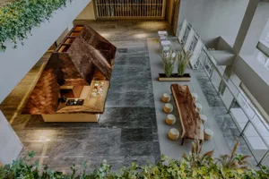 Open modern living area with a combined kitchen and dining space, tile flooring, chairs, a dining table, and a couch in the background, featuring a clean and minimalistic design with bright lighting