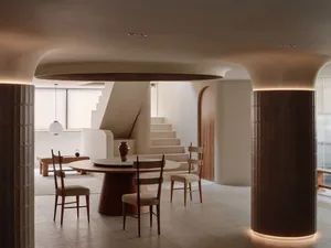 Open living area with dining table, chairs, couch, and kitchen cabinets in a well-designed interior space with comfortable and inviting atmosphere