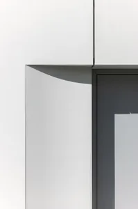 A building facade with a doorway and a concrete wall casting a shadow