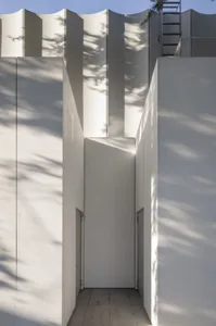 A serene entrance with two concrete pillars and an open doorway, set against a neutral background