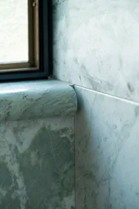 Bathroom with a green marble countertop, natural light from two windows, and a clean well-maintained atmosphere