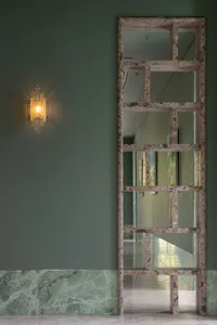 A room with a large mirror mounted on a wall, reflecting a green accent wall and other interior design elements