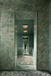 Elegant hallway with marble walls and floor, symmetrical doors, and overhead lighting