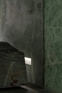 A dimly lit interior space with a large stone wall, creating a moody atmosphere