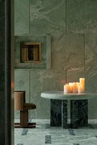 Cozy dining space with a green marble finish, a dining table, and three candles, set in a modern living area