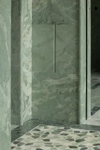 Bathroom with a green-tinted marble wall, two doors, and a sink, showcasing a well-designed space with a distinctive feature