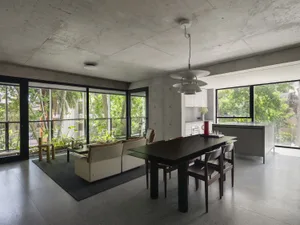 A modern living area with a large dining table, potted plants, and vases, creating a cozy atmosphere