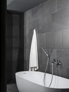 A clean and well-maintained bathroom with a freestanding white bathtub, showerheads, and a hanging towel