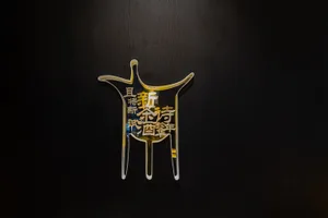 A modern restaurant or establishment features an oriental design on a wall with a yellow and black color scheme, made of glass, and complemented by artistic elements