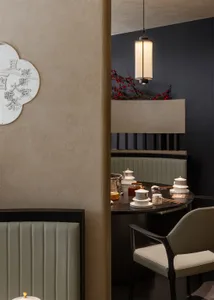 A cozy dining area with a stone wall, a table, chairs, potted plants, and decorative vases
