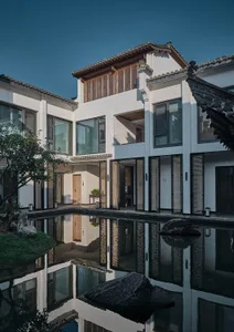 A sleek and elegant modern building with multiple windows, doors, and balconies, featuring a predominantly white exterior