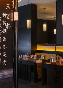 Cozy Asian restaurant interior with black walls, dining tables, chairs, and various cups and bowls on the tables