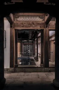 Traditional Asian building with wooden pillars and a stone archway, featuring multiple rooms with a pool and dining area