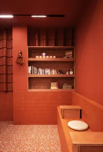 Cozy orange bathroom with a toilet, wooden shelf, and books, creating a warm and inviting atmosphere