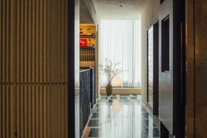 A calm and organized hallway with a black and white color scheme, featuring a tiled floor and two potted plants