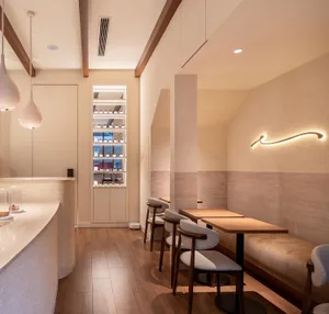 Cozy restaurant interior with wooden floors and walls, dining tables, and comfortable seating, featuring modern design and warm ambiance